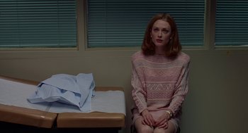 Movie still from “Safe” (1995), directed by Todd Haynes – A woman sitting on a chair next to a table; Medium shot, Low angle