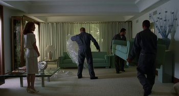 Movie still from “Safe” (1995), directed by Todd Haynes – Two men moving furniture in a living room; Wide shot, High angle