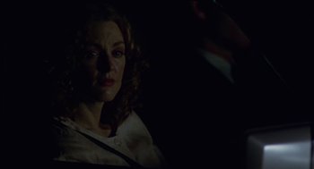Movie still from “Safe” (1995), directed by Todd Haynes – A woman in a white shirt is sitting in a dark room; Close Up shot, Over the shoulder angle