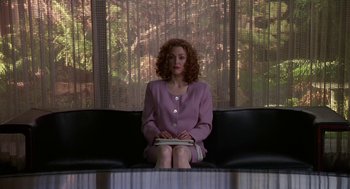 Movie still from “Safe” (1995), directed by Todd Haynes – A woman sitting on top of a black bench; Medium shot, Low angle