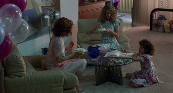 Movie still from “Safe” (1995), directed by Todd Haynes – Two women are sitting on a couch eating cake; Wide shot, High angle