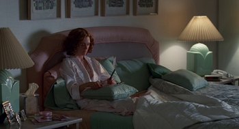 Movie still from “Safe” (1995), directed by Todd Haynes – A woman sitting on top of a couch writing on a piece of paper; Medium shot, High angle