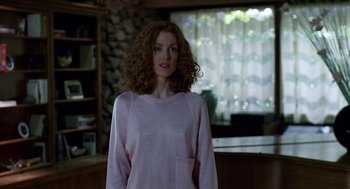 Movie still from “Safe” (1995), directed by Todd Haynes – A woman in a pink sweater standing in front of a window; Medium shot, Low angle