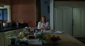 Movie still from “Safe” (1995), directed by Todd Haynes – A woman sitting at a kitchen table with a plate of fruit on the table; Medium shot, Low angle