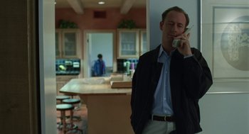Movie still from “Safe” (1995), directed by Todd Haynes – A man standing in a kitchen talking on a cell phone; Medium shot, Low angle