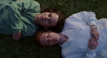 Movie still from “Safe” (1995), directed by Todd Haynes – Two people laying in the grass with their heads together; Close Up shot, Overhead angle