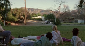 Movie still from “Safe” (1995), directed by Todd Haynes – A group of people laying in the grass near a road; Extreme Wide shot, High angle