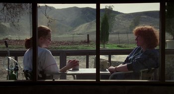 Movie still from “Safe” (1995), directed by Todd Haynes – Two people are sitting at a table with a view of mountains; Wide shot, Over the shoulder angle