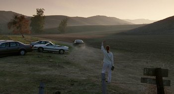 Movie still from “Safe” (1995), directed by Todd Haynes – A person standing in the middle of an open field waving; Extreme Wide shot, Low angle