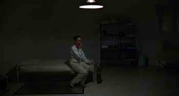 Movie still from “Safe” (1995), directed by Todd Haynes – A woman sitting on a bench in a dark room; Wide shot, High angle