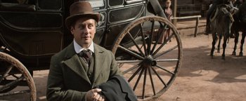 Movie still from “Godless” (2017), directed by Scott Frank – A man sitting in front of an old fashioned carriage; Medium shot, Low angle