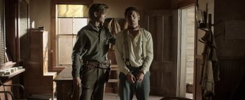Movie still from “Godless” (2017), directed by Scott Frank – Two men standing next to each other in a room; Medium shot, Over the shoulder angle