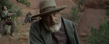 Movie still from “Godless” (2017), directed by Scott Frank – An old man with a white beard wearing a hat; Close Up shot, Over the shoulder angle