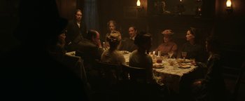 Movie still from “Godless” (2017), directed by Scott Frank – A group of people sitting around a table with food on top of it; Wide shot, High angle