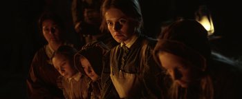Movie still from “Godless” (2017), directed by Scott Frank – A woman and two children are standing in a dimly - lit room; Close Up shot, Low angle