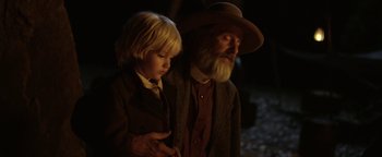 Movie still from “Godless” (2017), directed by Scott Frank – An older man and a young boy standing next to each other; Close Up shot, Over the shoulder angle