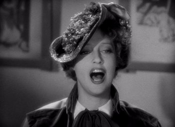 Movie still from “San Francisco” (1936), directed by W.S. Van Dyke – A woman wearing a hat with flowers on top of her head; Close Up shot, Low angle