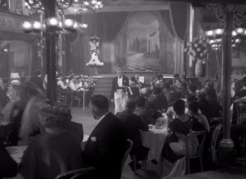 Movie still from “San Francisco” (1936), directed by W.S. Van Dyke – An old photo of a group of people sitting at a table; Wide shot, Low angle