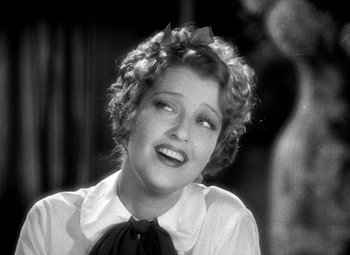 Movie still from “San Francisco” (1936), directed by W.S. Van Dyke – An old photo of a woman smiling for the camera; Close Up shot, Low angle
