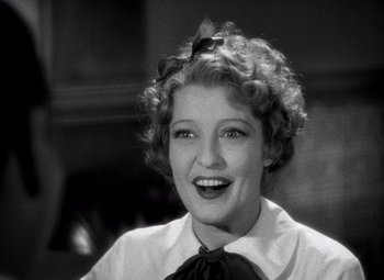 Movie still from “San Francisco” (1936), directed by W.S. Van Dyke – A black and white photo of a woman smiling; Close Up shot, Low angle