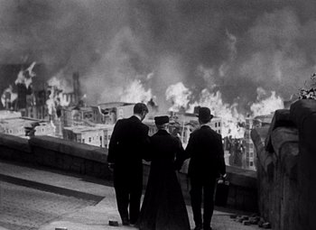 Movie still from “San Francisco” (1936), directed by W.S. Van Dyke – A group of people standing in front of a burning city; Wide shot, High angle