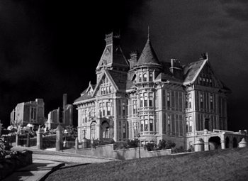Movie still from “San Francisco” (1936), directed by W.S. Van Dyke – An old building is shown in a black and white photo; Extreme Wide shot, Low angle