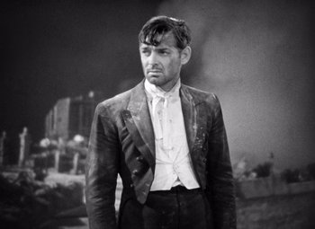 Movie still from “San Francisco” (1936), directed by W.S. Van Dyke – A man wearing a suit and tie standing in front of a building; Medium shot, High angle