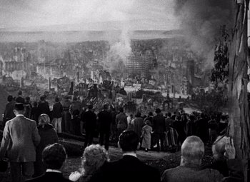 Movie still from “San Francisco” (1936), directed by W.S. Van Dyke – A group of people standing in a field with smoke billowing from the ground; Wide shot, High angle