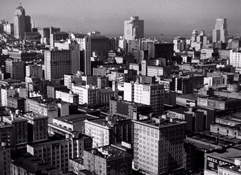 Movie still from “San Francisco” (1936), directed by W.S. Van Dyke – A black and white photo of a city with many tall buildings; Extreme Wide shot, High angle