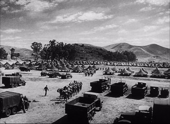 Movie still from “Sands of Iwo Jima” (1949), directed by Allan Dwan – An old black and white photo of a field full of military vehicles; Extreme Wide shot, High angle