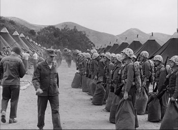 Movie still from “Sands of Iwo Jima” (1949), directed by Allan Dwan – An old black and white photo of a group of soldiers; Wide shot, Low angle