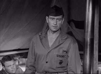 Movie still from “Sands of Iwo Jima” (1949), directed by Allan Dwan – A man in a military uniform standing in front of an army tent; Medium shot, Low angle