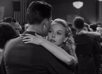 Movie still from “Sands of Iwo Jima” (1949), directed by Allan Dwan – A man and a woman are hugging in a room; Medium shot, Low angle