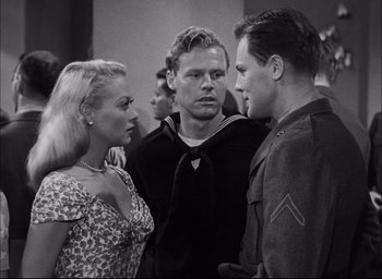 Movie still from “Sands of Iwo Jima” (1949), directed by Allan Dwan – A black and white photo of a group of men and a woman; Medium shot, Over the shoulder angle