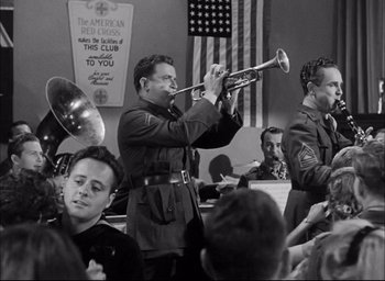 Movie still from “Sands of Iwo Jima” (1949), directed by Allan Dwan – A black and white photo of a man playing a trumpet; Medium shot, Low angle