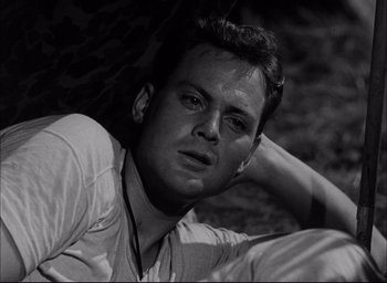 Movie still from “Sands of Iwo Jima” (1949), directed by Allan Dwan – Black and white photograph of a man laying on the ground; Close Up shot, High angle