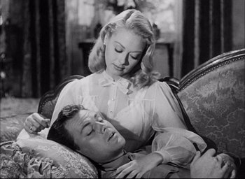 Movie still from “Sands of Iwo Jima” (1949), directed by Allan Dwan – A man and a woman are laying on a couch together; Medium shot, High angle