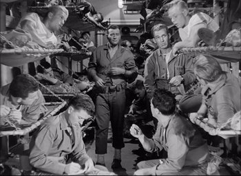 Movie still from “Sands of Iwo Jima” (1949), directed by Allan Dwan – A black and white photo of a group of men sitting around; Wide shot, High angle