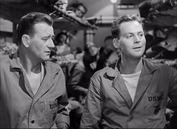 Movie still from “Sands of Iwo Jima” (1949), directed by Allan Dwan – A couple of men standing next to each other; Medium shot, Low angle