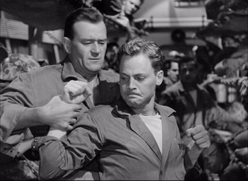 Movie still from “Sands of Iwo Jima” (1949), directed by Allan Dwan – A man is holding another man's arm; Medium shot, Low angle