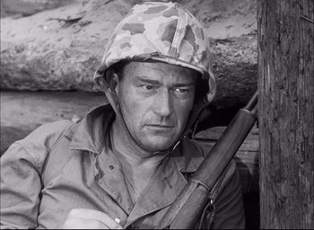 Movie still from “Sands of Iwo Jima” (1949), directed by Allan Dwan – A man with a rifle in his hand and wearing a helmet; Close Up shot, Low angle