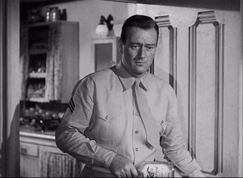 Movie still from “Sands of Iwo Jima” (1949), directed by Allan Dwan – A man in a uniform is holding something in his hand; Medium shot, Low angle