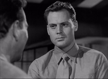 Movie still from “Sands of Iwo Jima” (1949), directed by Allan Dwan – A black and white photo of a man in a tie; Close Up shot, Over the shoulder angle