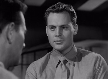 Movie still from “Sands of Iwo Jima” (1949), directed by Allan Dwan – A black and white photo of a man wearing a tie; Close Up shot, Over the shoulder angle