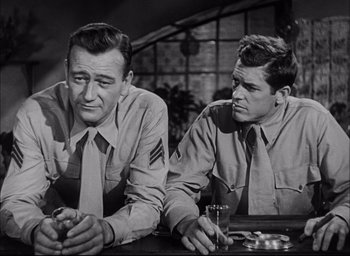 Movie still from “Sands of Iwo Jima” (1949), directed by Allan Dwan – A couple of men sitting next to each other at a table; Medium shot, Low angle