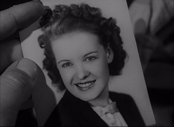 Movie still from “Sands of Iwo Jima” (1949), directed by Allan Dwan – An old photo of a young woman in a suit; Close Up shot, High angle