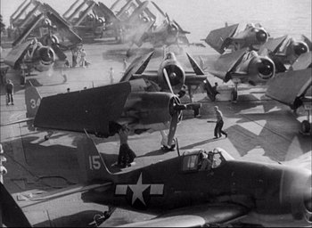Movie still from “Sands of Iwo Jima” (1949), directed by Allan Dwan – A black and white photo of airplanes on a runway; Wide shot, High angle