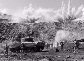Movie still from “Sands of Iwo Jima” (1949), directed by Allan Dwan – A black and white photo of a tank and soldiers; Extreme Wide shot, High angle