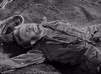 Movie still from “Sands of Iwo Jima” (1949), directed by Allan Dwan – A man laying on the ground in the dirt; Medium shot, High angle