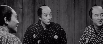 Movie still from “Sanjuro” (1962), directed by Akira Kurosawa – A man with a shaved head wearing a kimono; Close Up shot, Over the shoulder angle